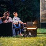 Family watching an outdoor movie powered by the Anker F2600 GaNPrime Powerstation on a lawn at night