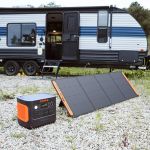 Jackery Explorer 1000 Plus Tragbare Powerstation mit Solarpanel neben einem Camper für autarke Stromversorgung