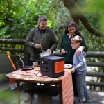 Jackery Explorer 1000 Plus Tragbare Powerstation versorgt Geräte auf einem Tisch im Outdoor-Bereich